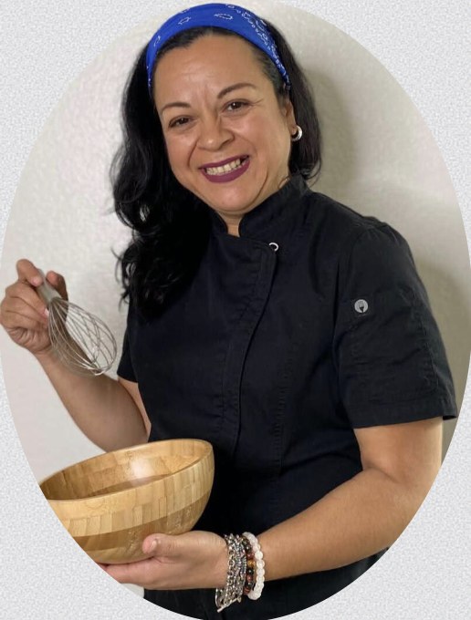 Chef Judith holding a whisk and wooden bowl